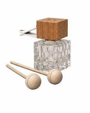 Clear glass bottle with wooden cap and two wooden mallets on a light gray background