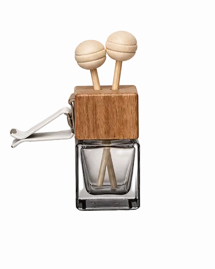 Glass diffuser with wooden top and two sticks on a light gray background