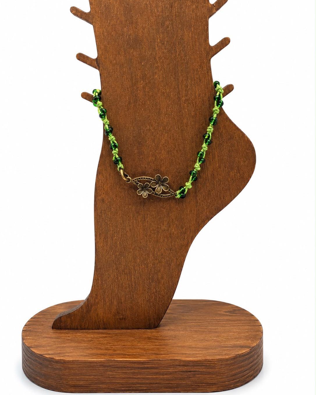 Necklace with green beads on a wooden stand against a white background