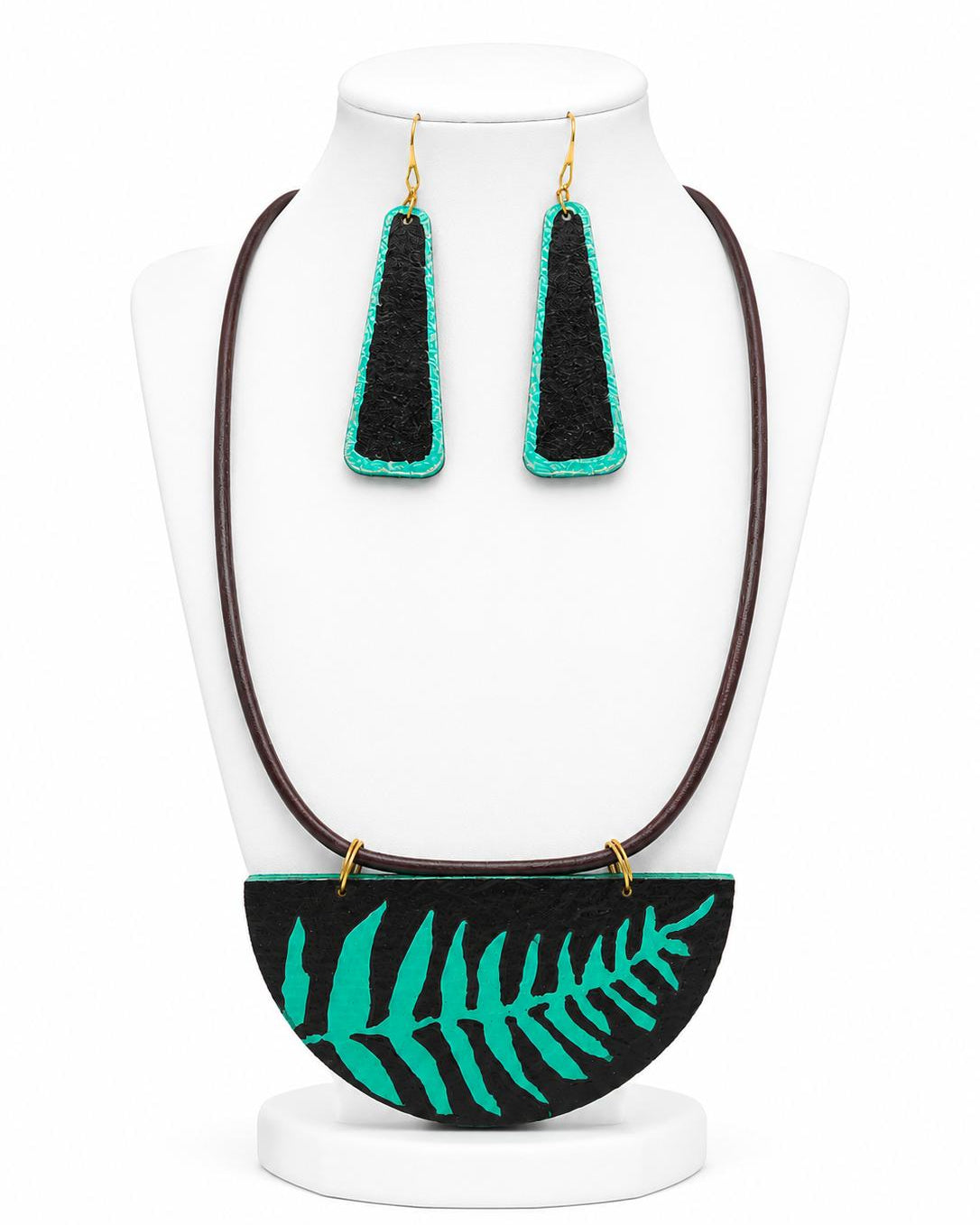 Black and green earrings on a white stand with a fern design