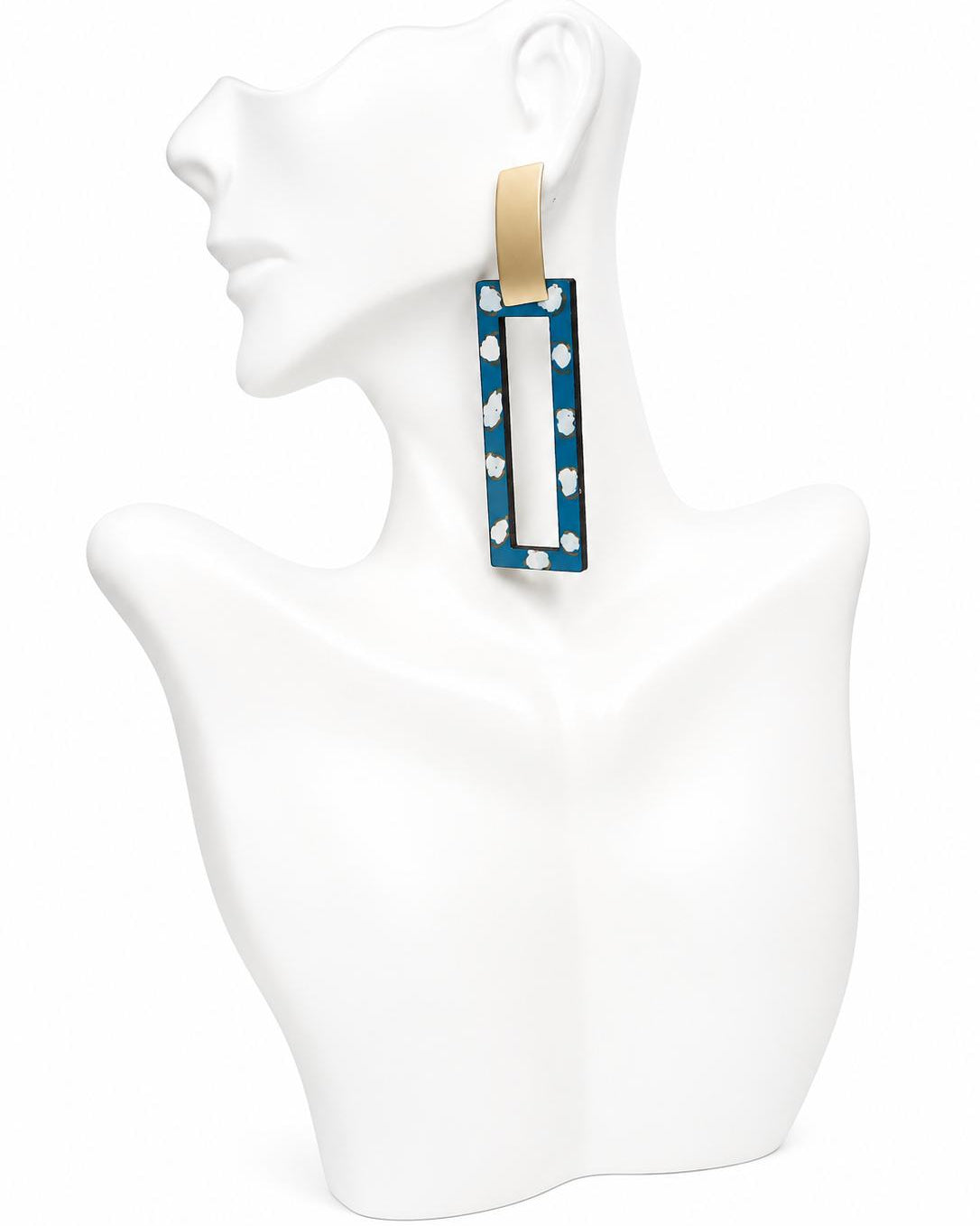 Blue and white polka dot earrings on a white mannequin bust.