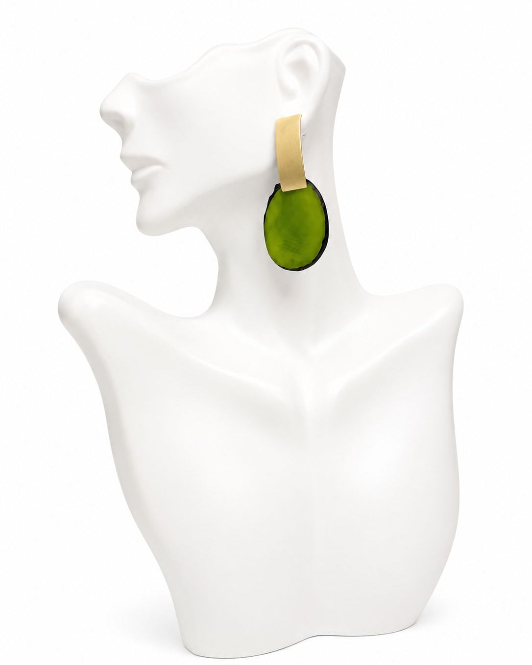Green earring on a white mannequin bust against a white background